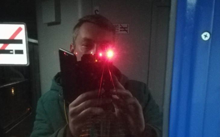 Mężczyzna robiący selfie z odbiciem czerwonych świateł.