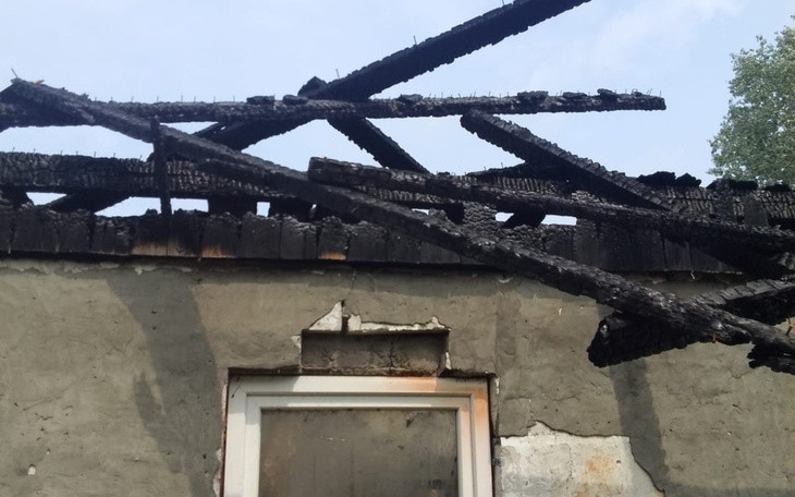 Zniszczony dach budynku, spalone belki na tle nieba.