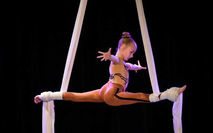 Dziecko w akrobatycznym kostiumie, w powietrzu.