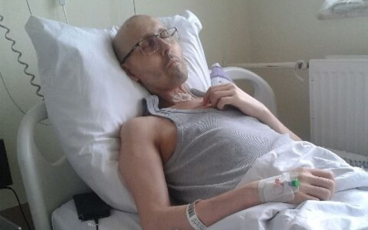 Mężczyzna leżący w szpitalnym łóżku, wygląda na zmęczonego.