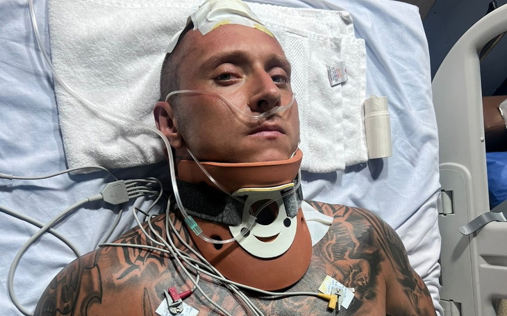 Mężczyzna leżący w szpitalu z opatrunkiem na szyi.