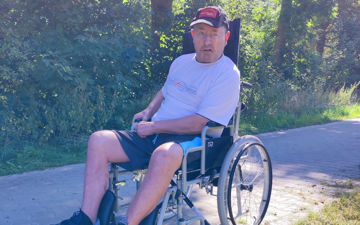 Mężczyzna na wózku inwalidzkim, odpoczywający na ścieżce.