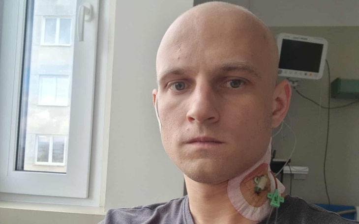 Mężczyzna w szpitalu z opatrunkiem na szyi.