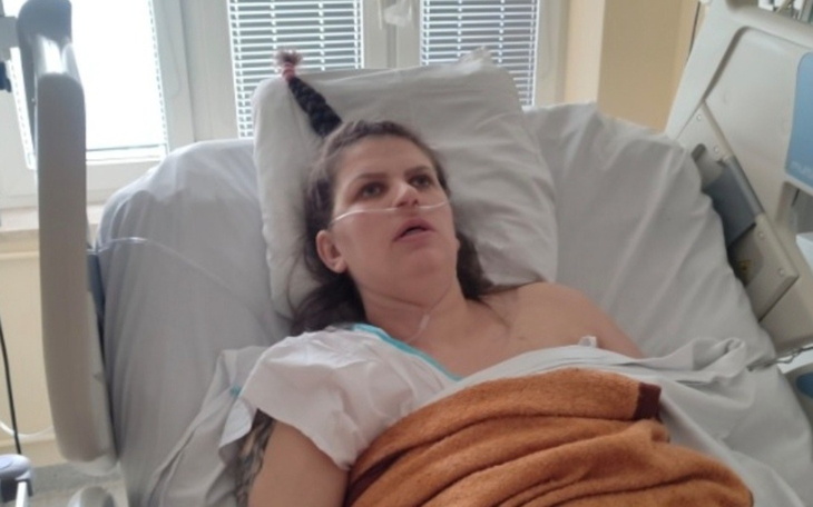 Kobieta leżąca w szpitalnym łóżku, z tlenem i opieką medyczną.