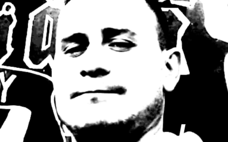 Czarnobiałe zdjęcie mężczyzny, z tajemniczym uśmiechem.