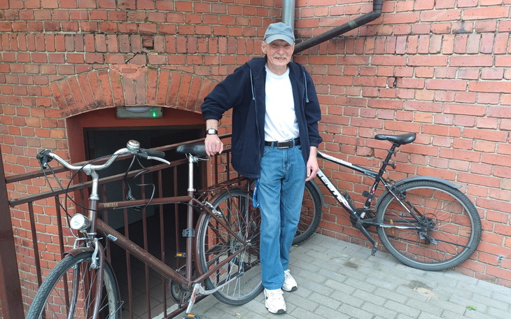 Mężczyzna z rowerami przy wejściu do budynku.