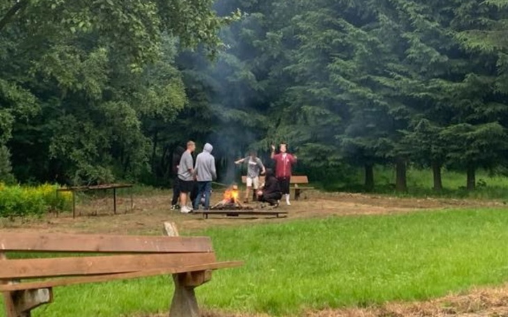 Grupa ludzi przy ognisku w lesie.