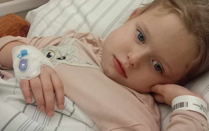 Chora dziewczynka leży w szpitalnym łóżku, zmartwiona i zmęczona.