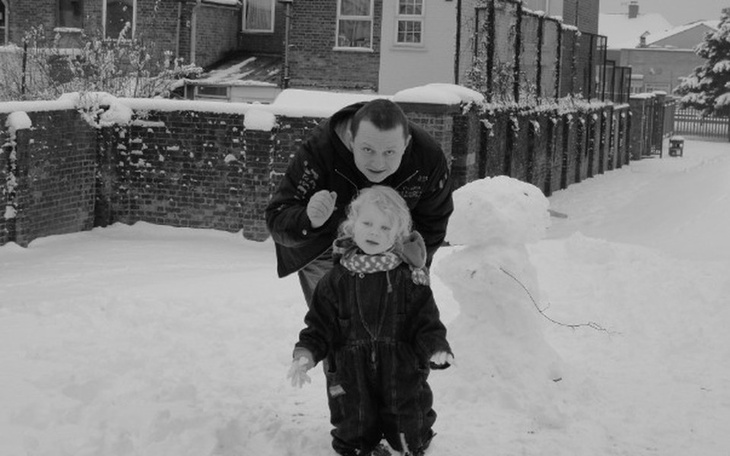 Dziecko i dorosły w zimowej scenerii, obok bałwan.