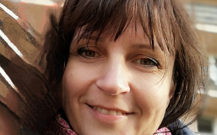 Portret uśmiechniętej kobiety w szaliku, z bliskim ujęciem twarzy.