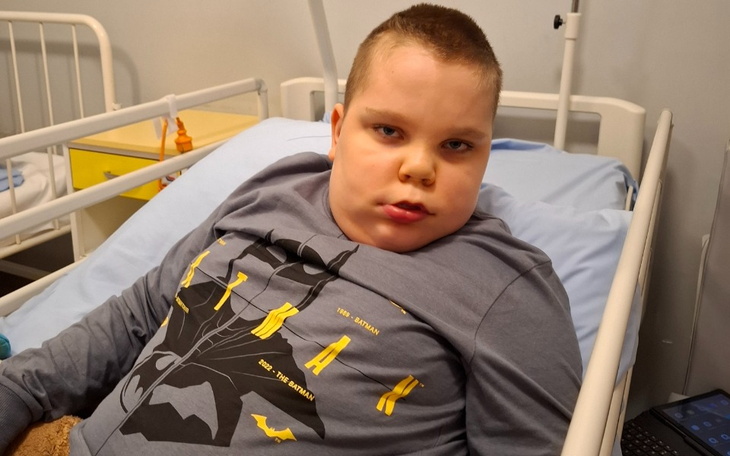 Chłopiec w szpitalu, siedzący na łóżku.