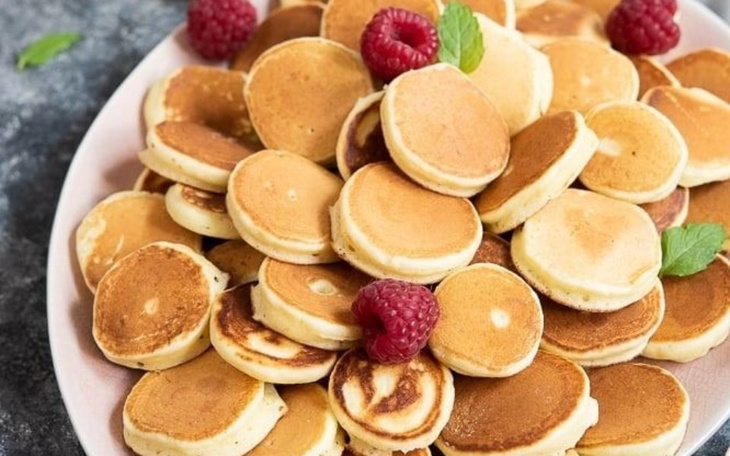 Talerz z małymi naleśnikami i owocami.