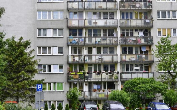 Budynek mieszkalny z balkonami i zielenią wokół.