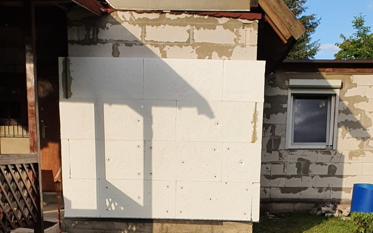 Biała ściana z płytami styropianowymi na budynku.