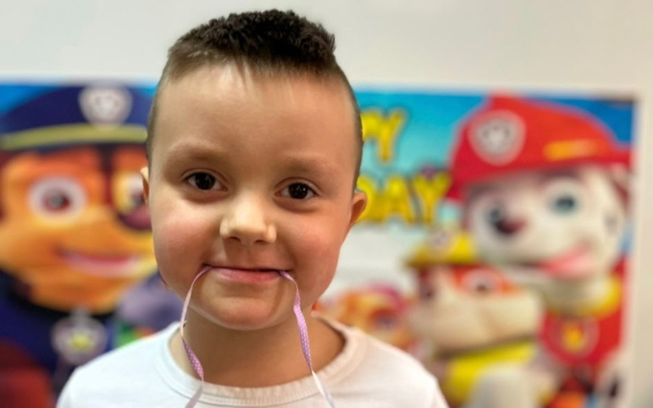 Uśmiechnięty chłopiec z urodzinowym tłem, trzymający sznurki.