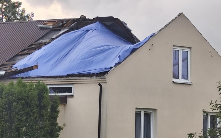 Uszkodzony dach pokryty niebieską folią po burzy.