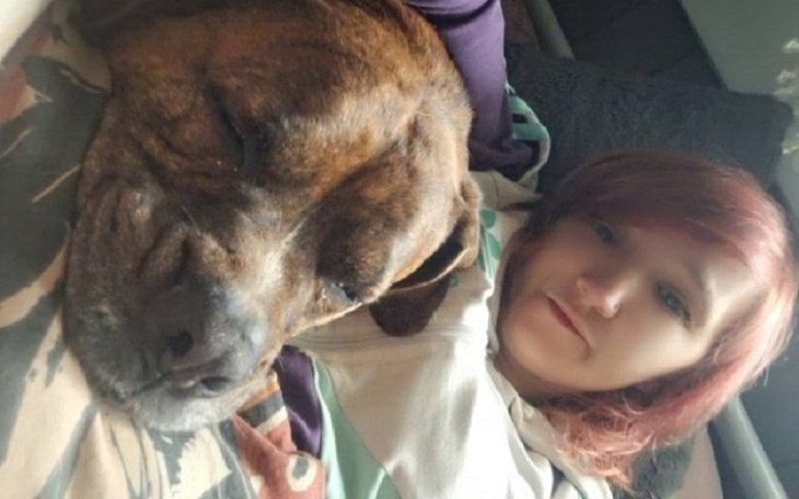 Młoda kobieta z psem, oboje odpoczywają na łóżku.