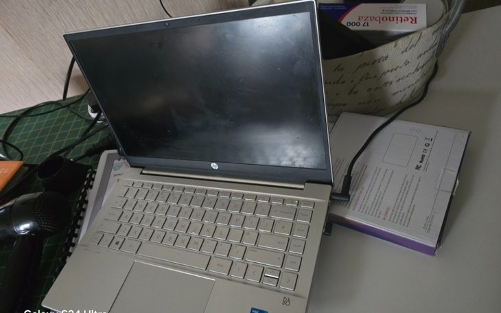 Zamknięty laptop na biurku, otoczony przedmiotami.