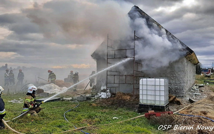 Strażacy gaszący pożar w budynku, otoczeni dymem.