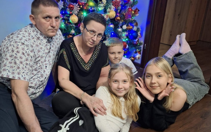 Rodzina pozująca przy choince, w świątecznym nastroju.