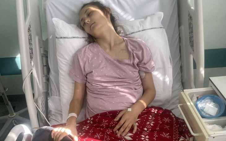 Młoda kobieta leży w szpitalnym łóżku, wygląda na zmęczoną.