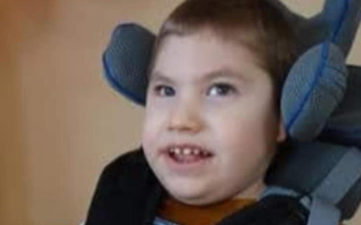 Chłopiec w wózku, uśmiechający się do kamery.