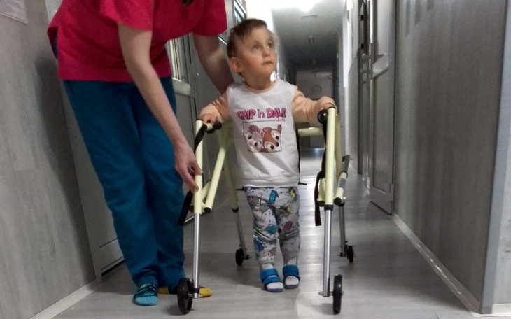 Chłopiec uczący się chodzić z pomocą wózka.