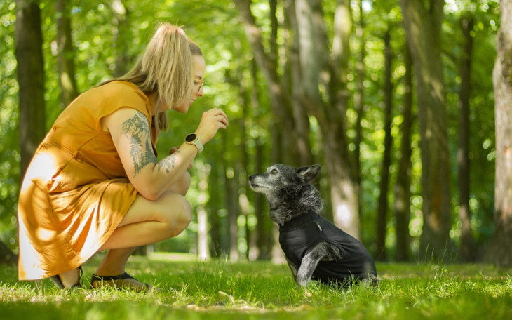Kobieta w parku, bawiąca się z psem.