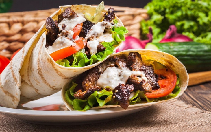 Pyszne kebaby z sałatą i sosem na talerzu.