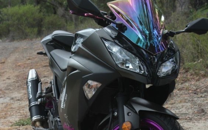 Motocykl sportowy z kolorowym kaskiem na tle przyrody.