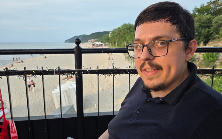 Mężczyzna siedzący na tarasie z widokiem na plażę.