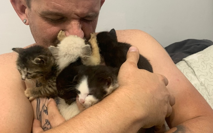 Mężczyzna przytulający kocięta, pełen miłości i radości.