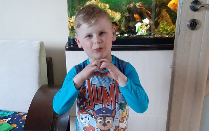 Chłopiec w piżamie z postaciami z bajek, robiący serce z rąk.