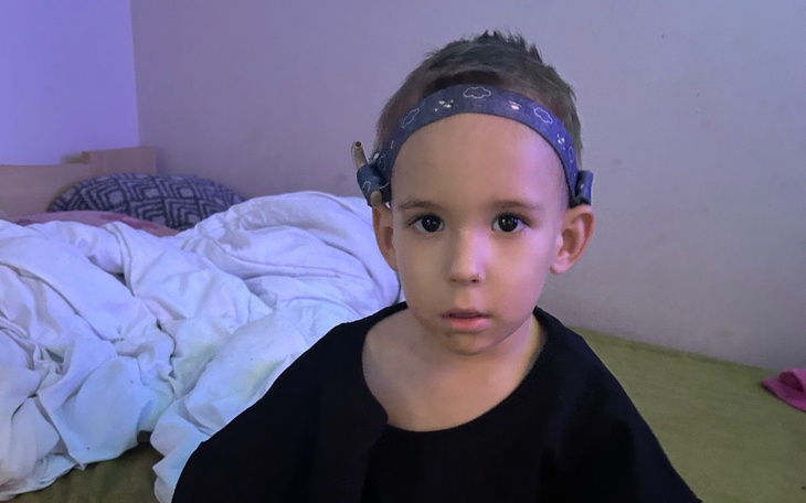 Mały chłopiec siedzi na łóżku, wygląda na zamyślonego.