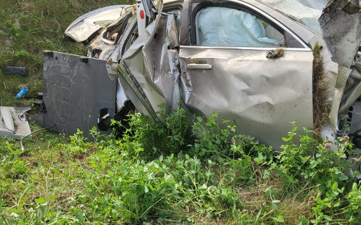 Zniszczony samochód po wypadku, otoczony roślinnością.