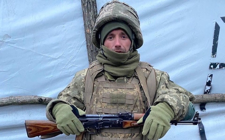 Żołnierz w mundurze z bronią, stojący w obozie.