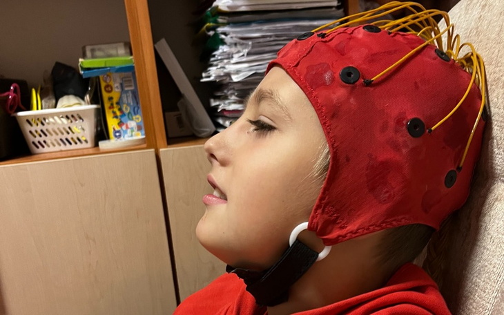 Chłopiec w czepku EEG, z zainteresowaniem patrzy w bok.