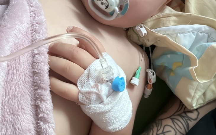 Dziecko z rurkami medycznymi, leżące na łóżku szpitalnym.