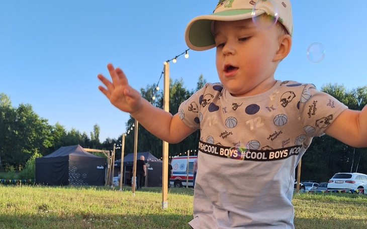 Mały chłopiec bawiący się na świeżym powietrzu, w tle balony.