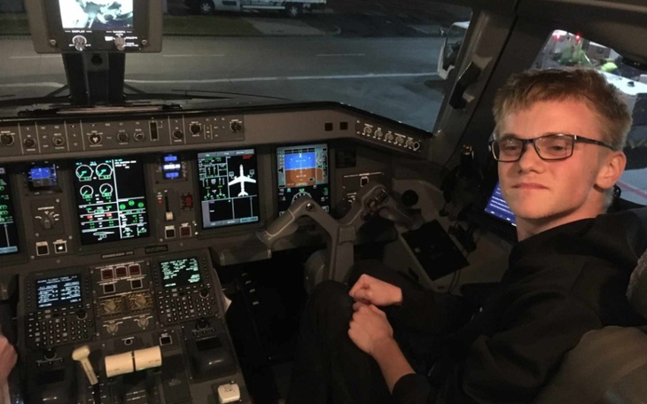 Młody mężczyzna w kokpicie samolotu, uśmiechnięty.