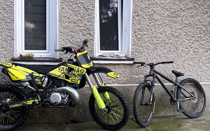 Motocykl i rower stojące obok siebie przy ścianie budynku.