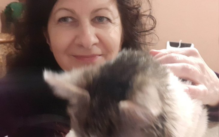 Kobieta z uśmiechem, trzymająca kota w ramionach.