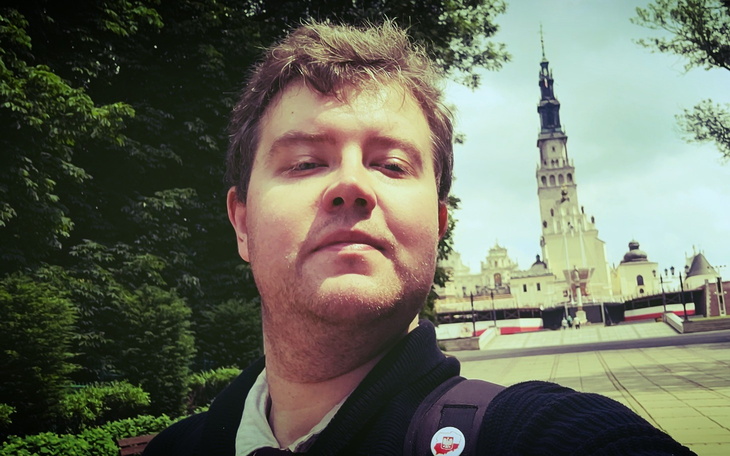 Mężczyzna na tle klasztoru jasnogórskiego w Częstochowie.