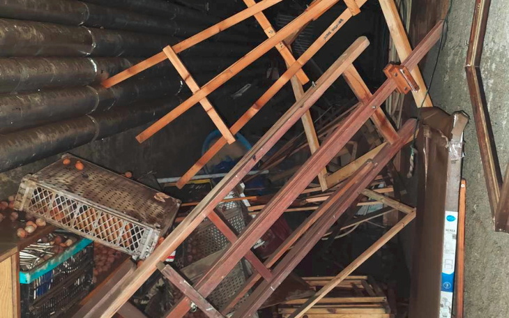 Zniszczona przestrzeń z przewróconymi meblami i przedmiotami.