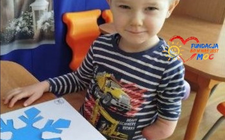 Chłopiec z uśmiechem, trzymając kolorowy papier.