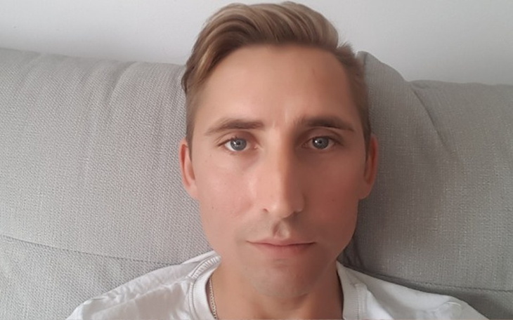 Mężczyzna siedzi na kanapie, patrząc w kamerę.
