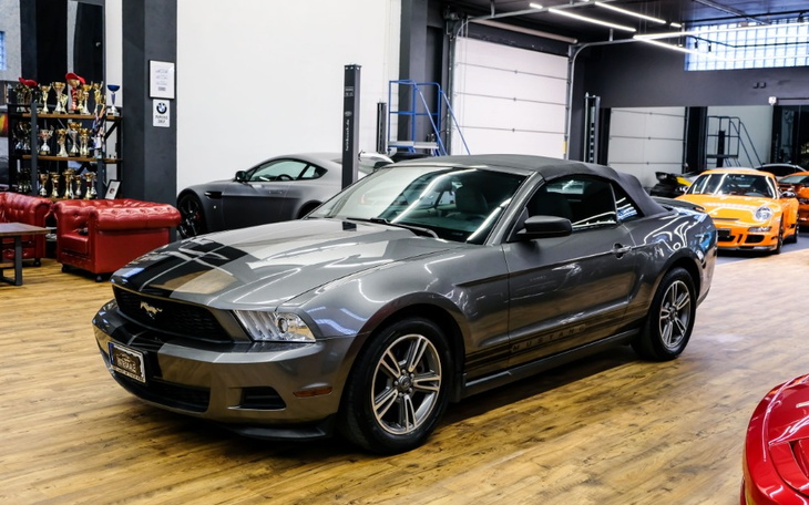 Szary kabriolet Mustang w nowoczesnym wnętrzu salonu samochodowego.