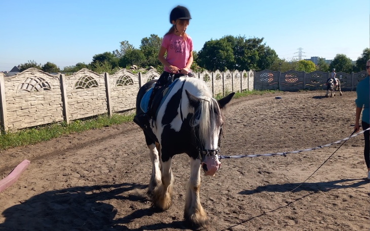 Dziewczynka jeździ na koniu na placu do jazdy.