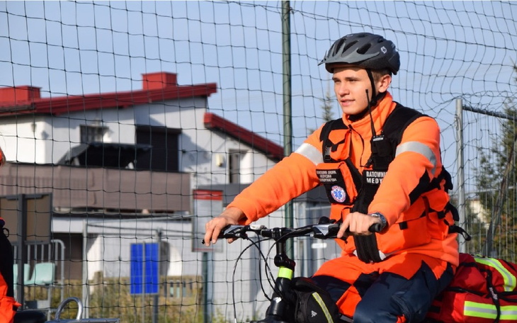 Mężczyzna na rowerze, ubrany w odzież ratunkową, w akcji.
