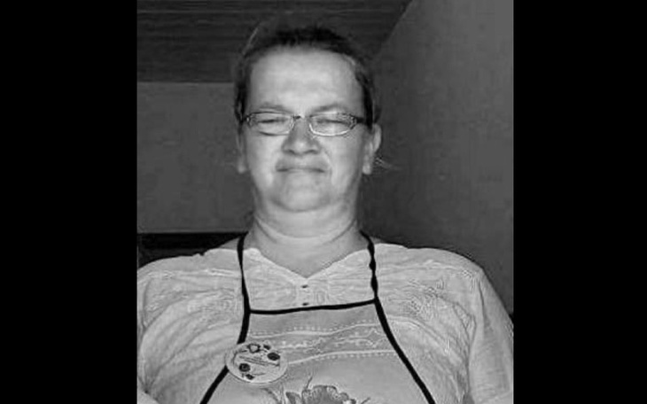 Osoba w fartuchu, uśmiechająca się do kamery.